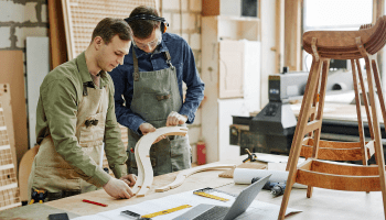 Two carpenters measuring wood in a workshop