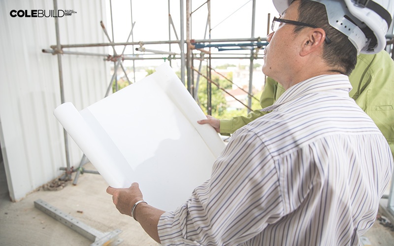home builder holding a large white paper overseeing a project
