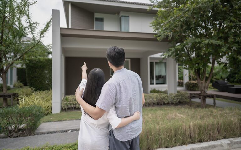 Asian Couple embracing outside their new home