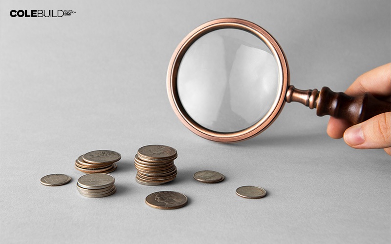 magnifying glass beside a pile of coins